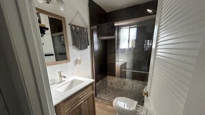 Un baño pequeño con lavabo, inodoro y zona de ducha.