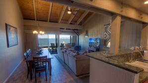 A spacious living area with a dining table, sofa, and kitchen counter.