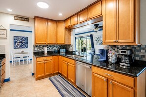 A modern kitchen with wooden cabinets, a stainless steel dishwasher, and a coffee maker.