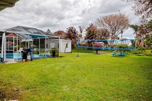 Un pati posterior amb una piscina, una terrassa coberta i una taula de picnic.