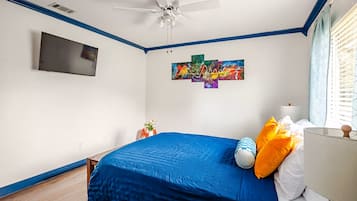 A bedroom with a bed, a ceiling fan, a mounted TV, and a wall art piece.