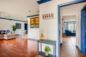 A spacious living area with hardwood flooring, a sofa, a coffee table, and a dining area with a white table and chairs.