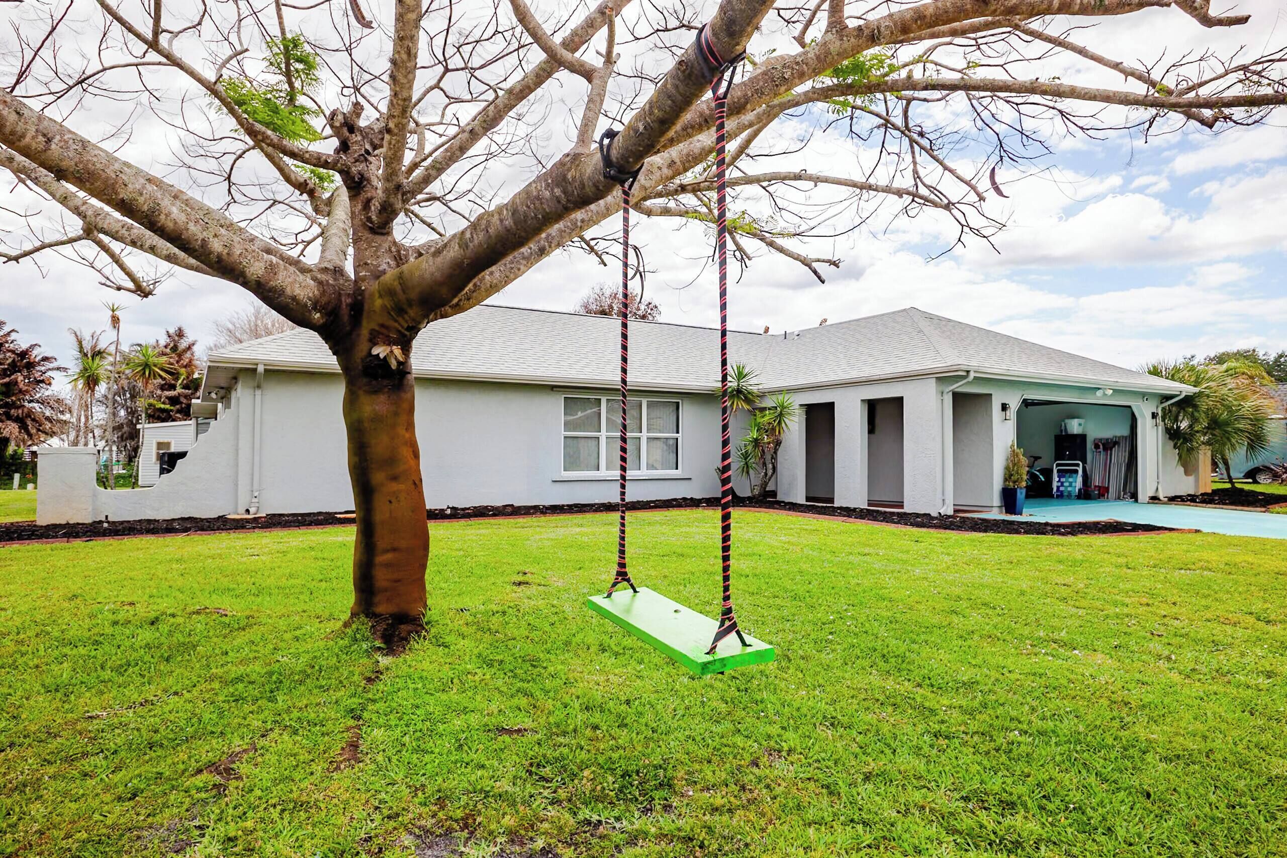 A residential house with a swing set in the yard.