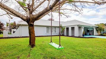 A residential house with a swing set in the yard.