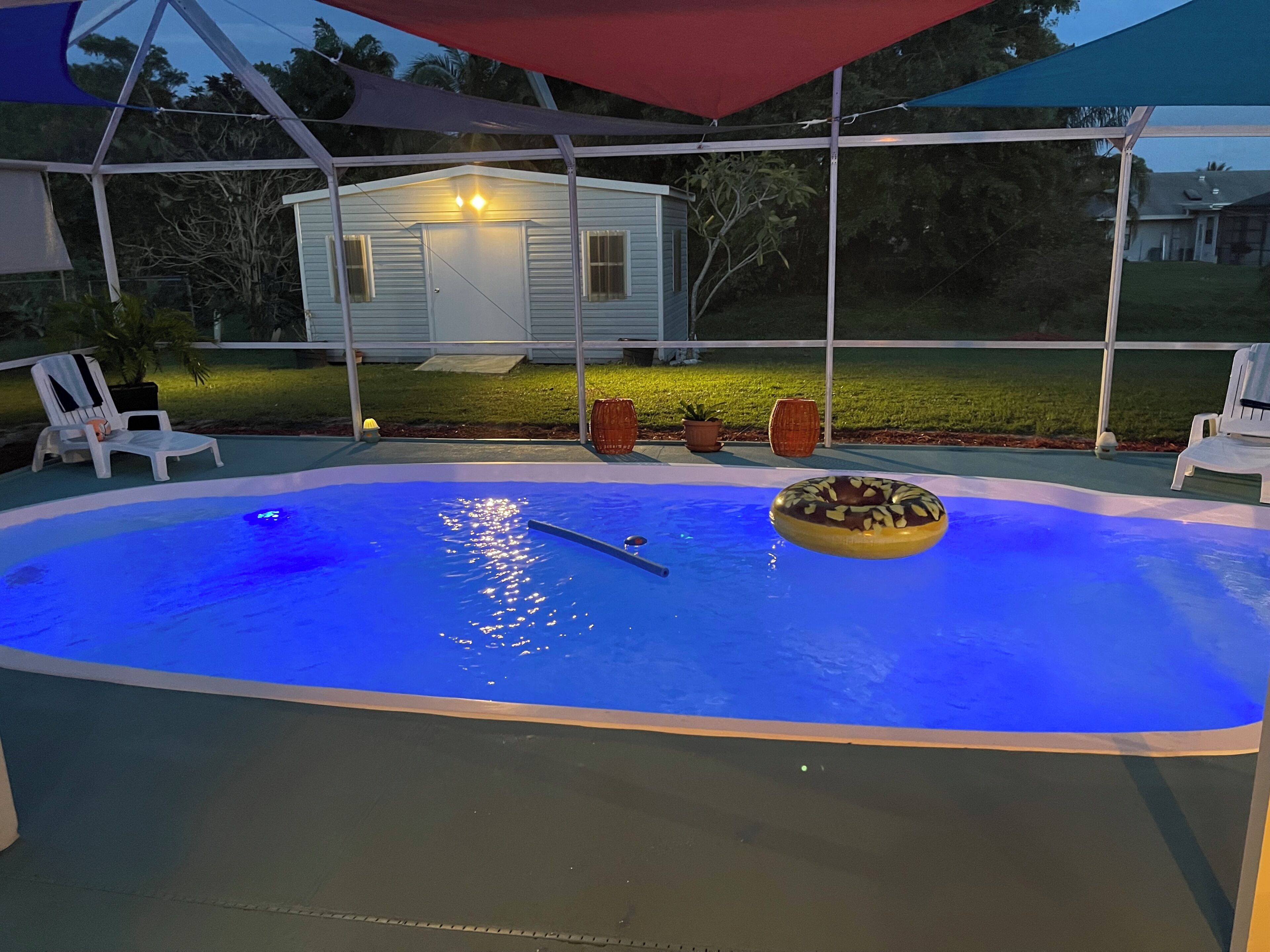 A swimming pool with a donut float, surrounded by lounge chairs and umbrellas.
