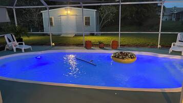 A swimming pool with a donut float, surrounded by lounge chairs and umbrellas.