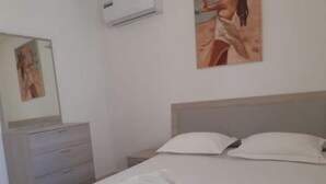 A bedroom with a bed, two pillows, a nightstand, a dresser, and a mirror.