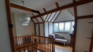 A spacious room with wooden beams, a chandelier, and a large window. - Beautiful old rustic house on two acres of overlooking fields in the back garden (Winchester)