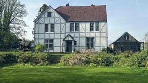 A two-story house with a gabled roof and a front porch. - Beautiful old rustic house on two acres of overlooking fields in the back garden (Winchester)