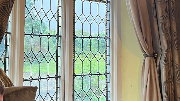 A room with a large window featuring a geometric pattern, a sofa, and curtains. - Beautiful old rustic house on two acres of overlooking fields in the back garden (Winchester)