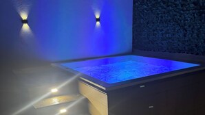 Een modern buitenzwembad met een verlicht waterobject en trappen naar het zwembad.