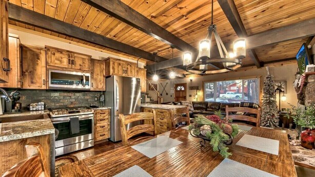 A rustic kitchen with wooden cabinets, a stainless steel refrigerator, and a large island with a built-in oven.