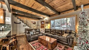 A cozy living room with a leather sectional sofa, a wooden coffee table, and a Christmas tree.