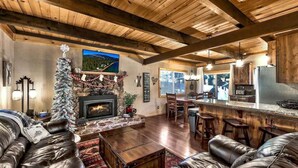 A cozy living room with a fireplace, leather sofas, a Christmas tree, and a stone fireplace surround.