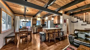 A spacious kitchen with wooden beams, a dining area with a wooden table and chairs, and a leather sofa.