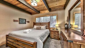 A bedroom with a wooden bed, a nightstand, a dresser, and a large mirror.