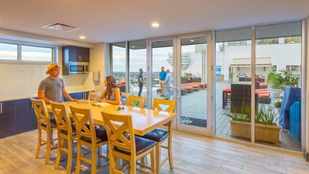 Une cuisine moderne dotée d’une grande table à manger et de chaises, d’un four à micro-ondes et offrant une vue sur la ville grâce à de grandes fenêtres.