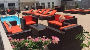 Un espace piscine sur le toit, avec des chaises longues et une piscine.