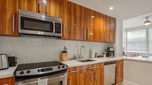 Una cocina moderna con armarios de madera, electrodomésticos de acero inoxidable y encimera blanca.