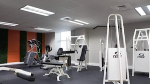 Un gimnasio con máquinas de cardio, equipo de levantamiento de pesas y una máquina de la marca Cyrex montada en la pared.