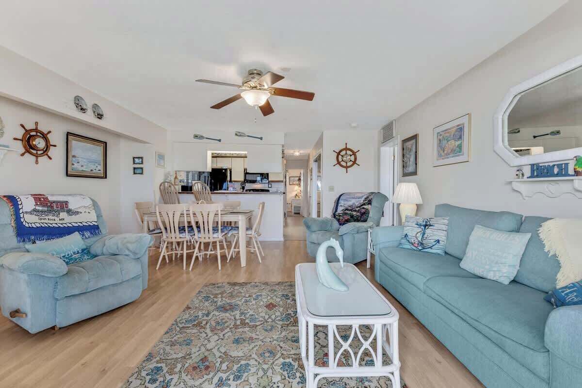 A living room with two sofas, a coffee table, a ceiling fan, and a rug.