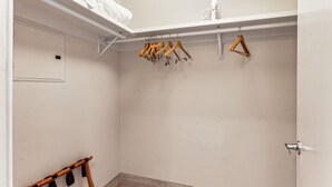 Un dressing accessible sans porte, avec des cintres en bois, une tringle blanche et une porte blanche.