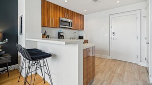 Una cocina moderna con armarios de madera, microondas integrado y una barra con taburetes.