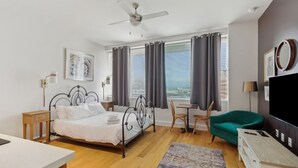 A modern bedroom with a bed, a desk, a chair, a TV, and a ceiling fan. - Urban Retreat Escape Studio (New Orleans)