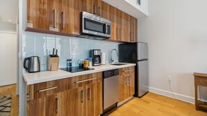 A modern kitchen with wooden cabinets, stainless steel appliances, and a white countertop. - Urban Retreat Escape Studio (New Orleans)