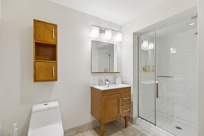 Une salle de bain moderne avec un meuble-lavabo en bois, un grand miroir et une douche à parois de verre.