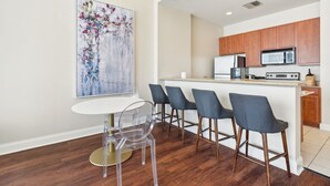 Une cuisine moderne avec des meubles en bois, un four à micro-ondes et un four encastré. On y trouve également un coin repas avec une table blanche et quatre chaises.