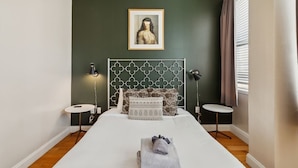 Un lit bien fait, avec une couette blanche et une serviette pliée au pied du lit.