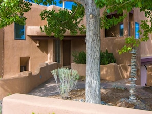 A building with a stucco exterior, a tree, and a rock garden.