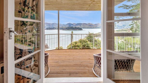 Eine offene Holzterrasse mit Blick auf einen See und Berge.