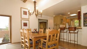 Uma sala de jantar com mesa e cadeiras de madeira, um lustre e vista para o exterior.