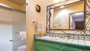 Un baño con inodoro, lavabo, espejo y ducha.