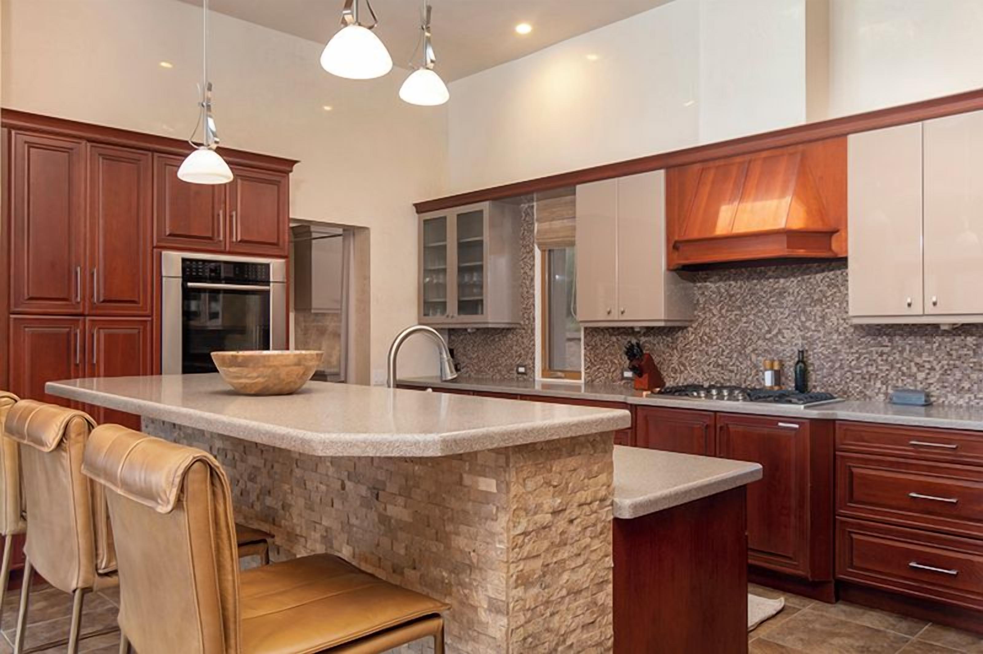 A modern kitchen with a central island, stainless steel appliances, and wooden cabinetry.