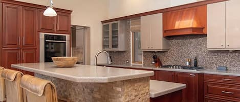A modern kitchen with a central island, stainless steel appliances, and wooden cabinetry.