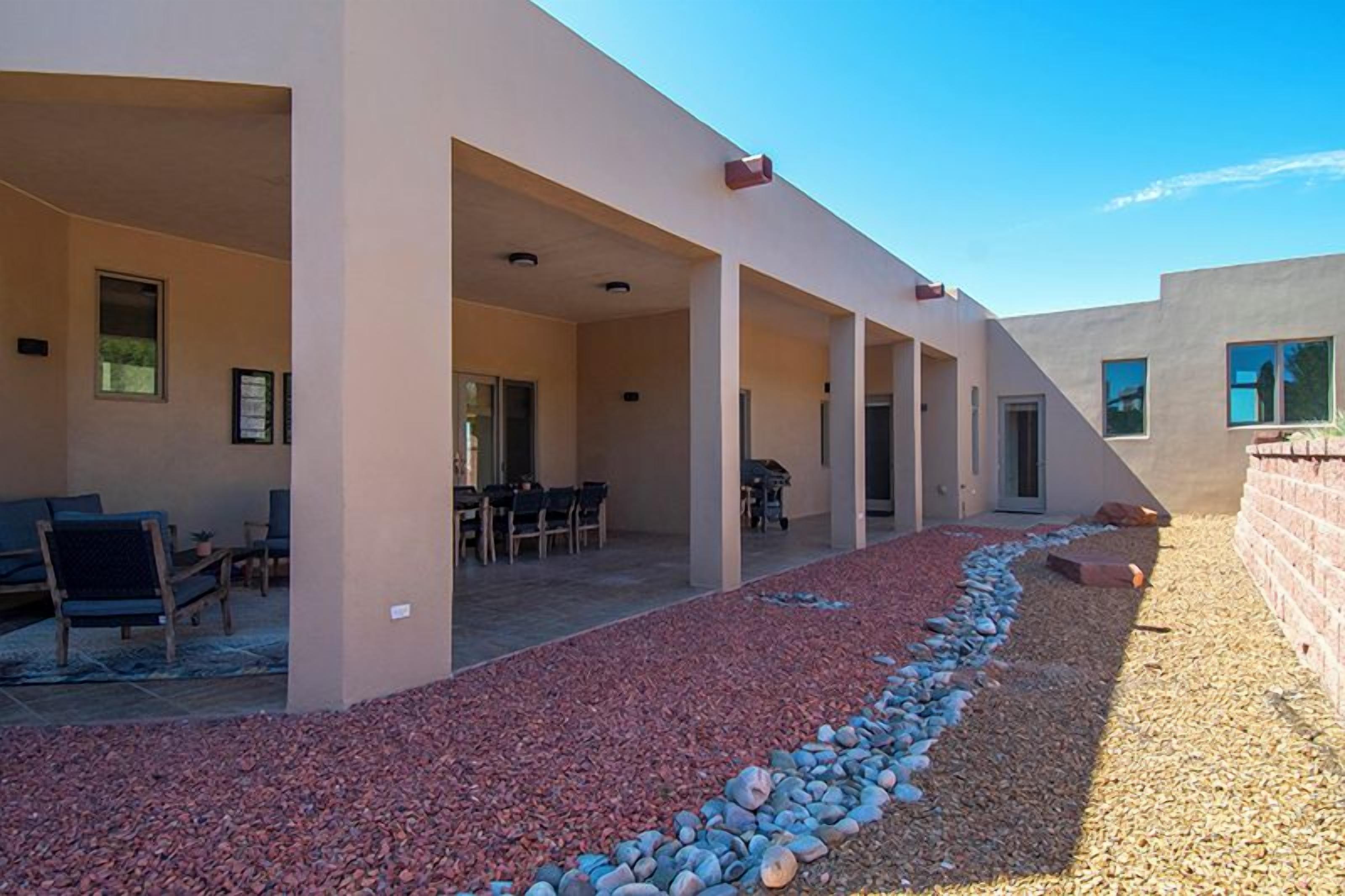 A covered outdoor area with a patio, seating, and a gravel path.