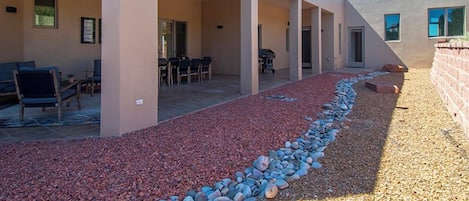 A covered outdoor area with a patio, seating, and a gravel path.