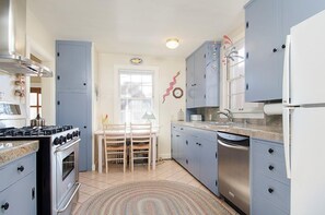 Une cuisine équipée d’une cuisinière à gaz, d’un four, d’un évier et d’appareils électroménagers modernes.