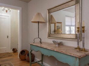 A bathroom with a white door, a vanity with a bowl sink, a mirror with a decorative frame, and a lamp.