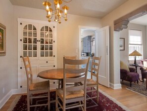 Un coin repas avec une table ronde et quatre chaises, un lustre et un tapis à motifs.