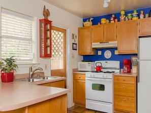 A kitchen with wooden cabinets, a white stove, a microwave, and a red kettle.