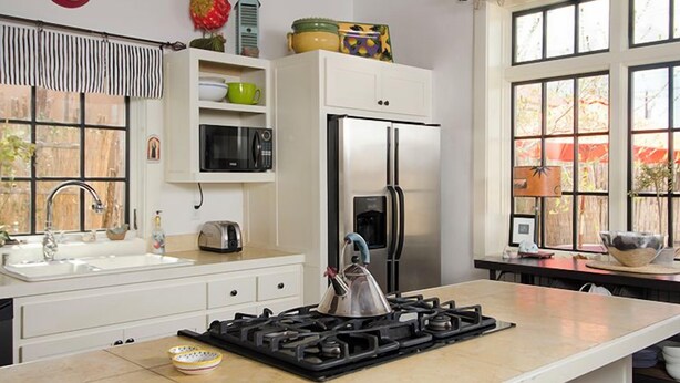Cozinha equipada com fogão, micro-ondas, frigorífico e janela com vista.