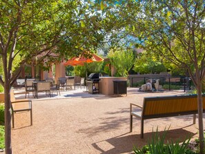 An outdoor patio area with seating, a barbecue grill, and a covered seating area.