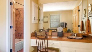 Une salle de bain avec une baignoire, une douche, un meuble-lavabo et une chaise.