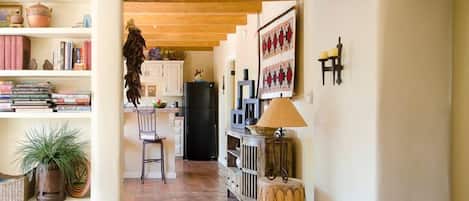 Une cuisine chaleureuse avec un plafond en bois, un coin repas avec une chaise et un réfrigérateur.