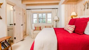 A bedroom with a large bed, a bedside table, a chair, and a window with curtains. - Jewel of Circle Drive (Santa Fe)