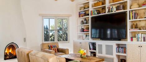 Una sala de estar con chimenea, un sofá, un televisor y una estantería.